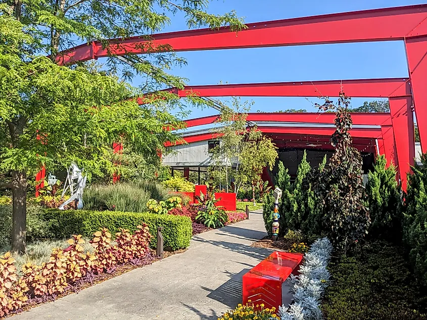 Modern garden with red steel structures and greenery.